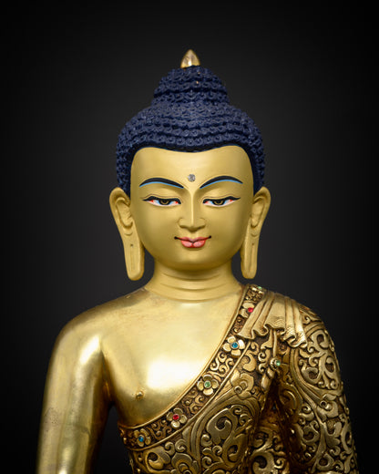Golden Shakyamuni Buddha sculpture featuring a finely gold painted face and intricate floral carvings on the monastic robe.