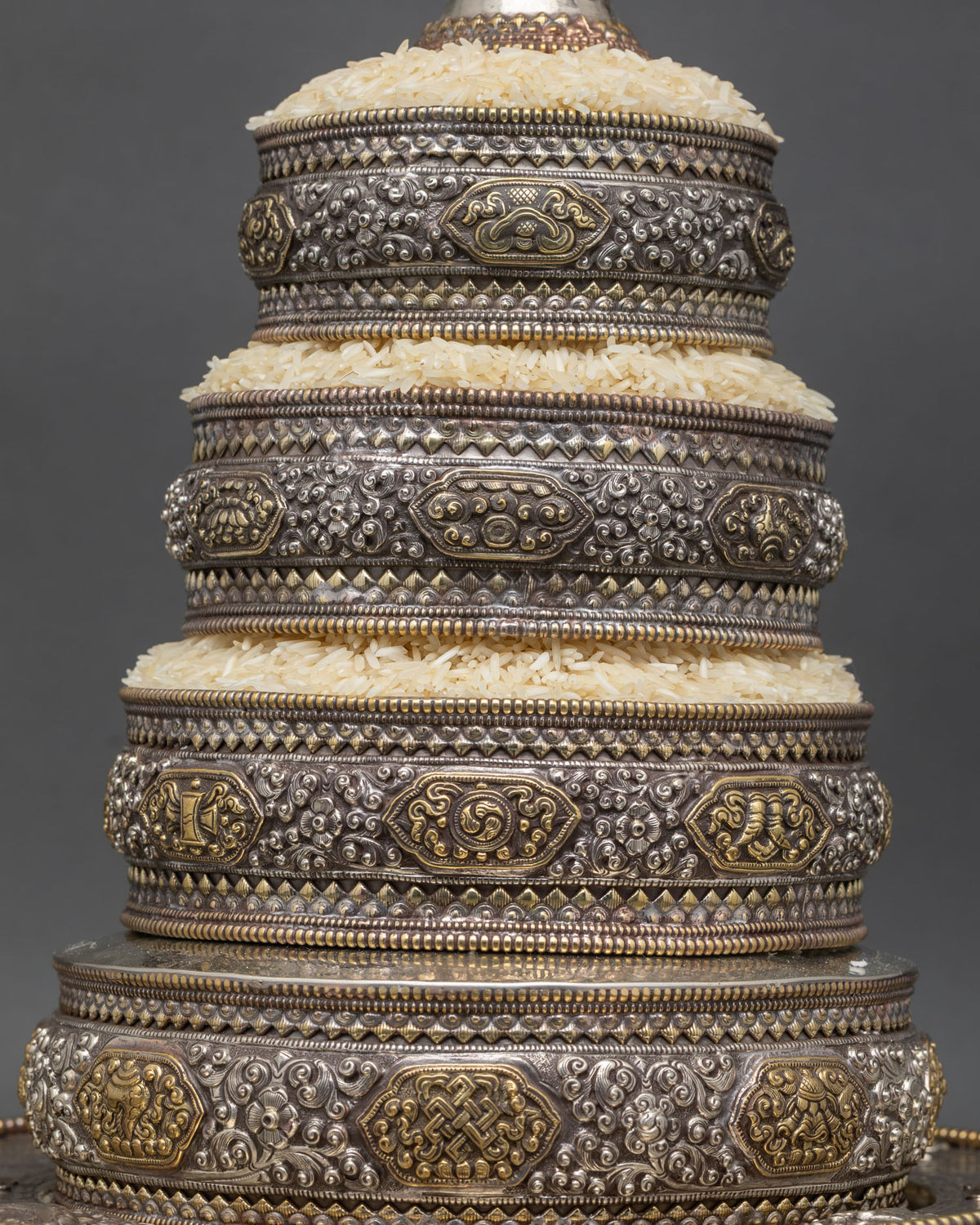 Graduated tiers of a Tibetan rice offering mandala with gold-gilded Eight Auspicious Symbols