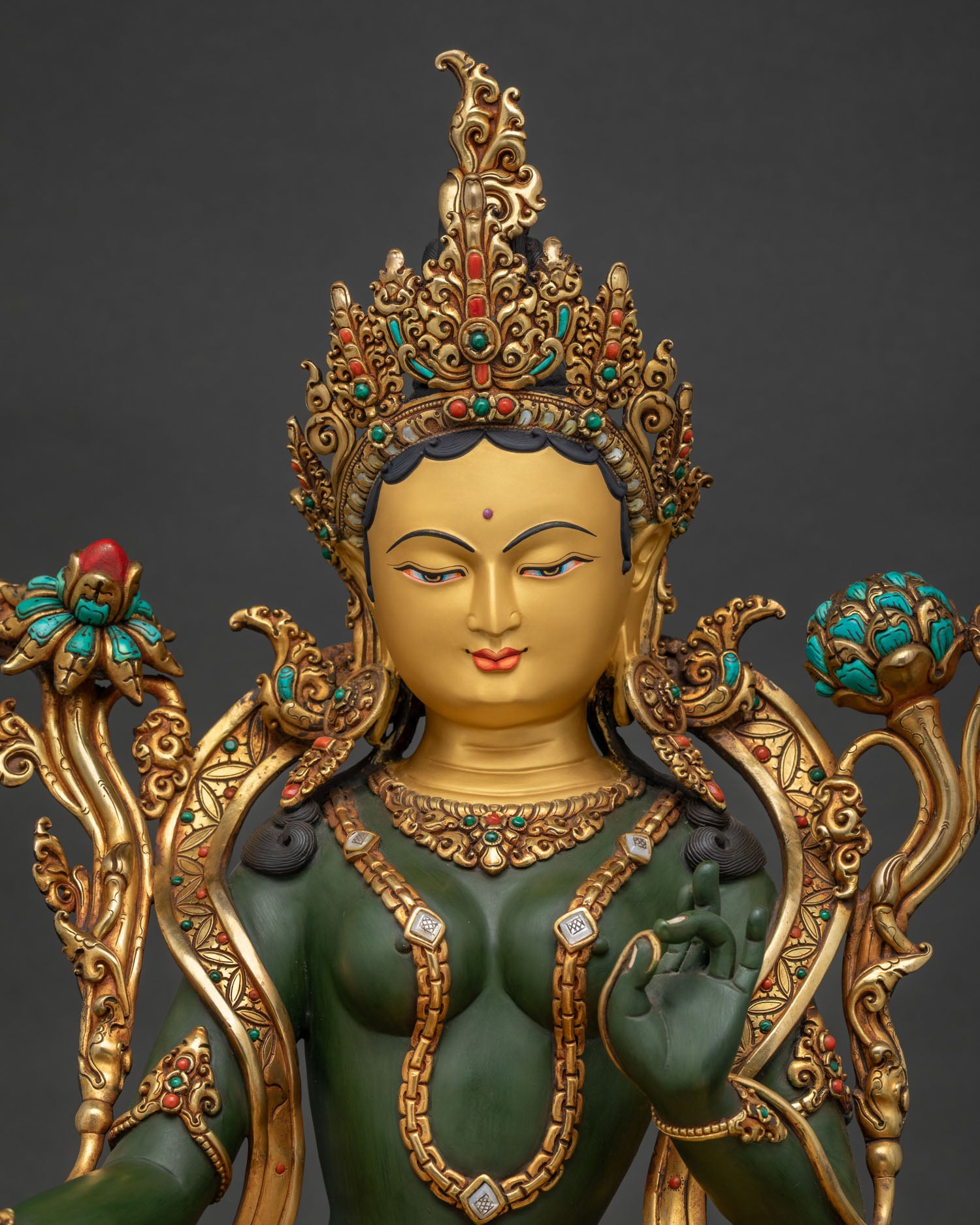 Green Tara Buddhist statue close-up showing turquoise coral inlaid crown and painted details