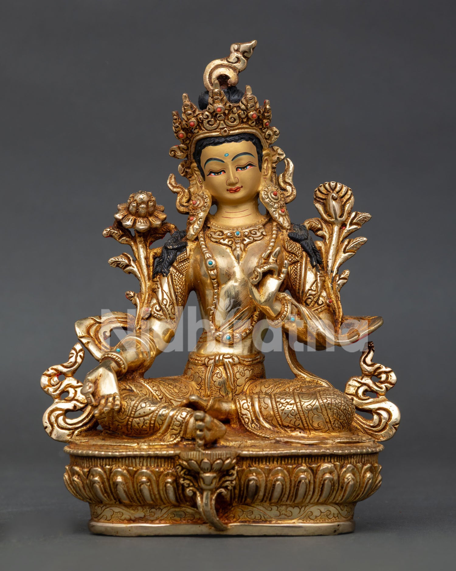 Green Tara Buddhist statue seated on lotus throne with extended right leg and lotus flower.