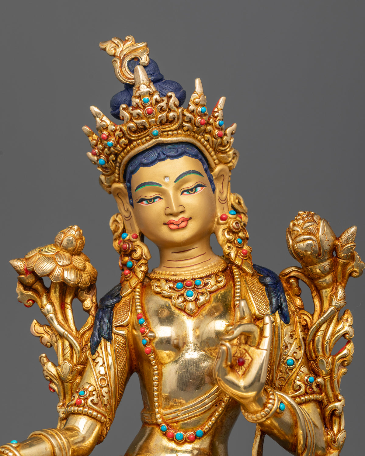 Green Tara Buddhist statue with gold painted face five jeweled crown and intricate sacred ornaments.