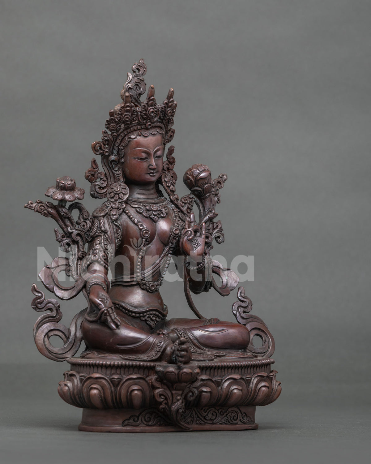 Green Tara deity sculpture displaying Varada Mudra and holding an utpala lotus flower