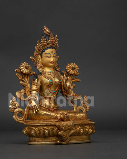 Green Tara seated on lotus pedestal holding blue utpala flower.