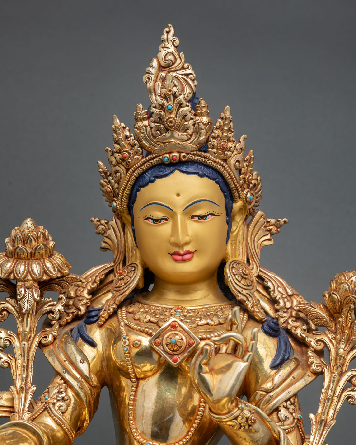 Green Tara statue close up view Nepal handmade copper sculpture gold gilded face detail with serene expression and inlaid turquoise coral lapis lazuli stones