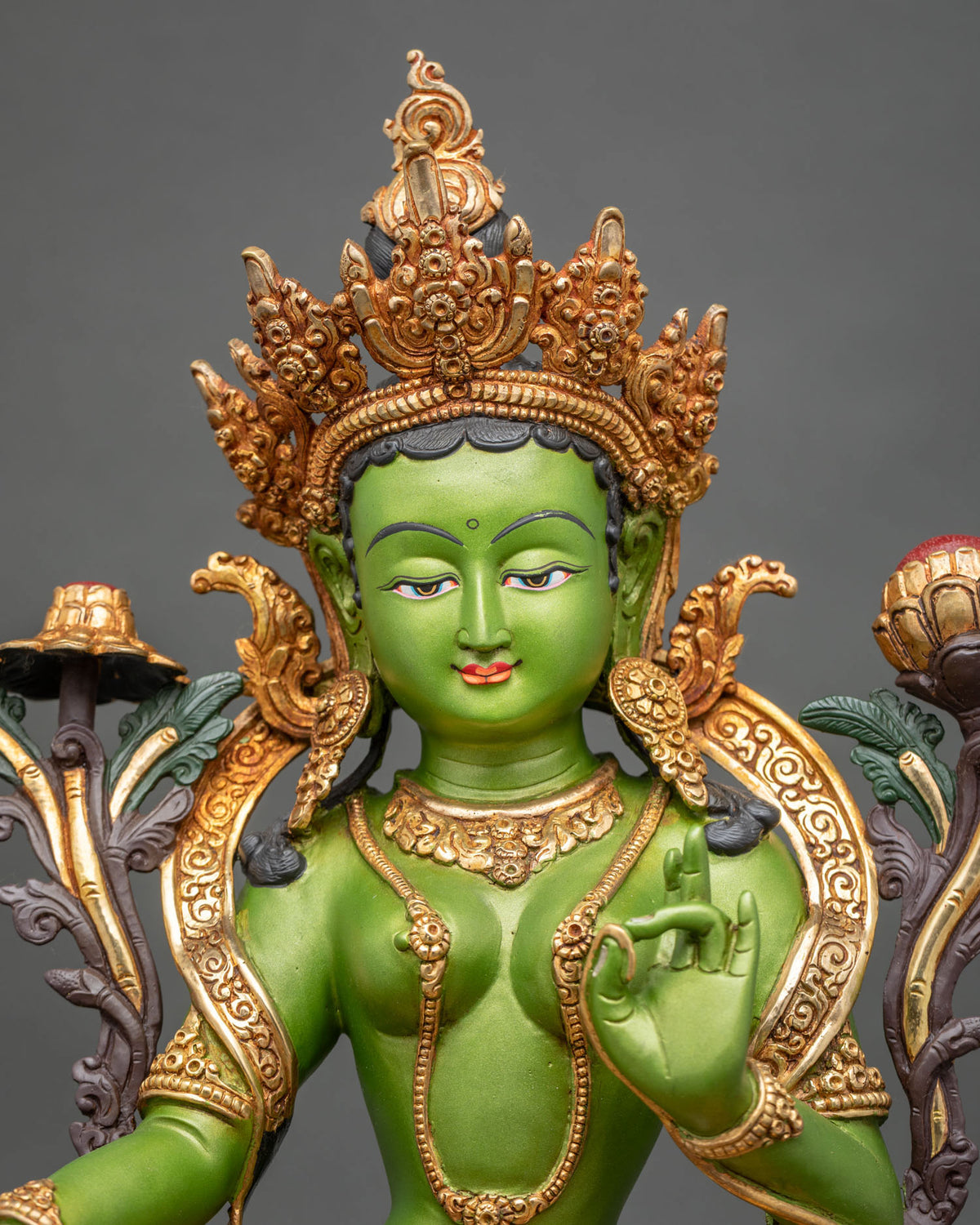 Green Tara statue close up showing ornate jewel crown and serene face.