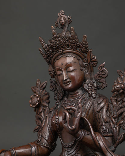 green tara statue close up showing jeweled crown and hand carved details.