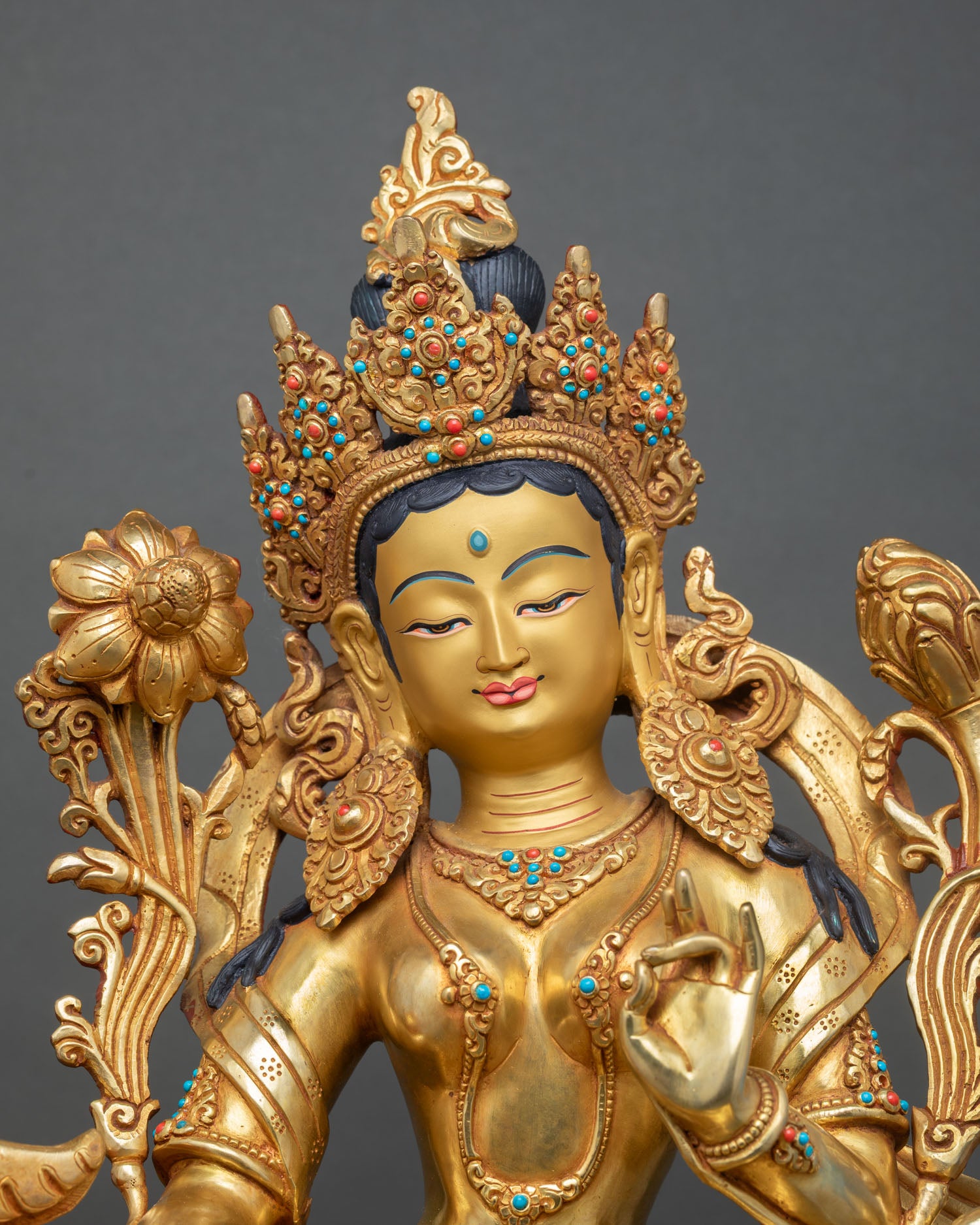 Green Tara statue close up view with gold painted face semi precious stones and utpala flower detail