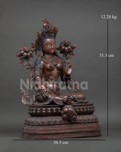 Green Tara statue, extended leg resting on lotus flower, compassionate deity, oxidized copper sculpture