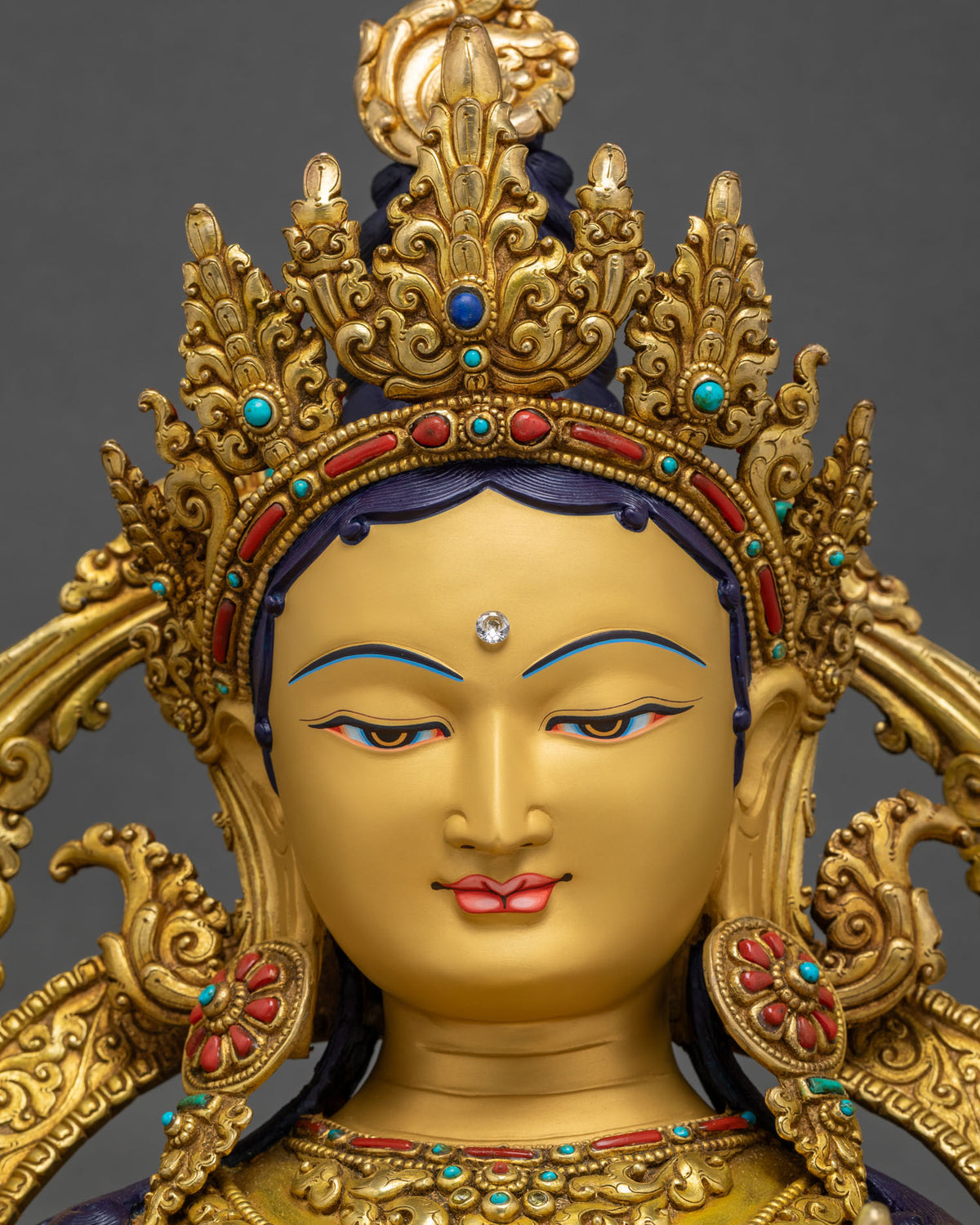 Green Tara Statue face close-up, serene gold-painted compassion expression
