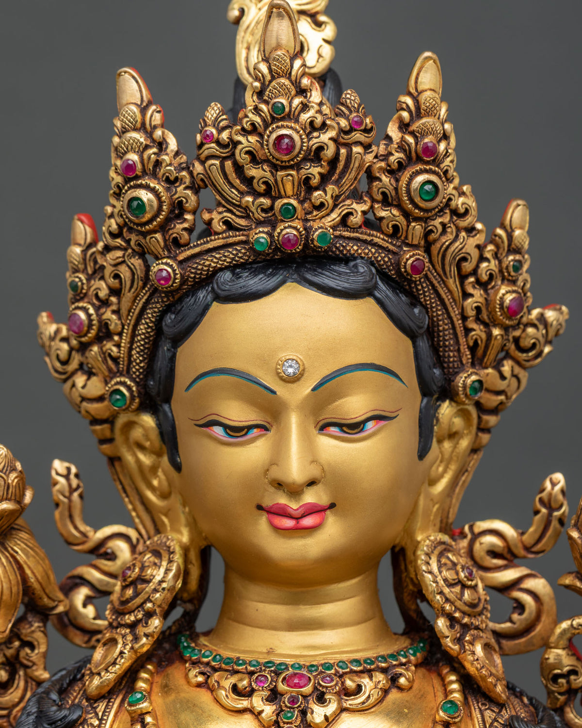 Green Tara statue face close up with serene expression and delicately painted features