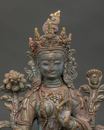 Green Tara statue holding blooming lotus stem with compassionate serene expression.