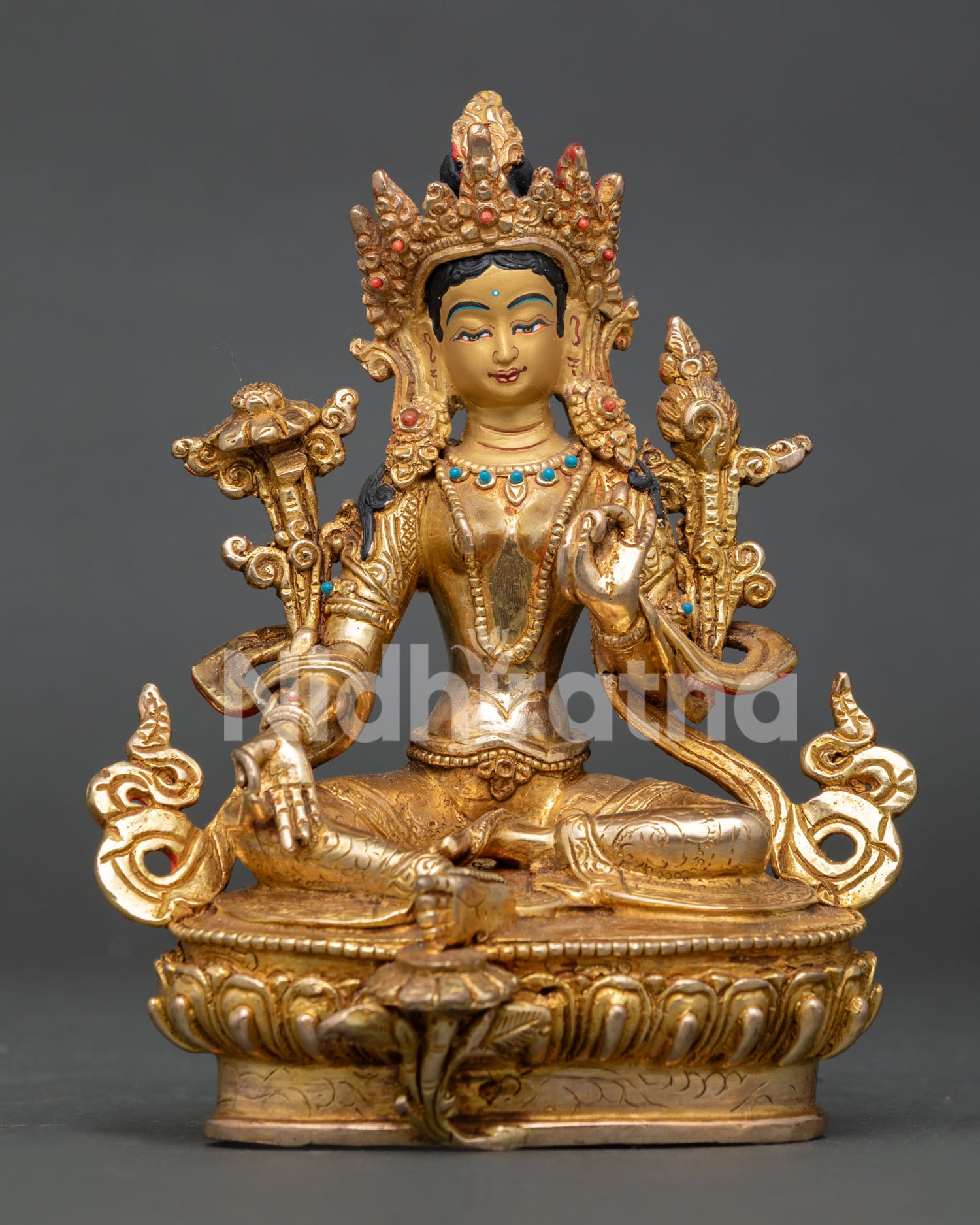 Green Tara statue seated on a lotus throne with an extended leg and coral stone decoration.