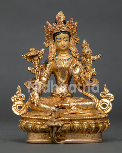 Green Tara statue seated on a lotus throne with an extended leg and coral stone decoration.