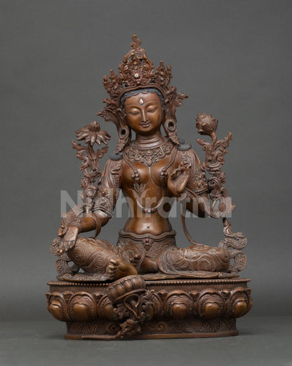 Green Tara statue seated on lotus seat with oxidized copper finish and blue lotus