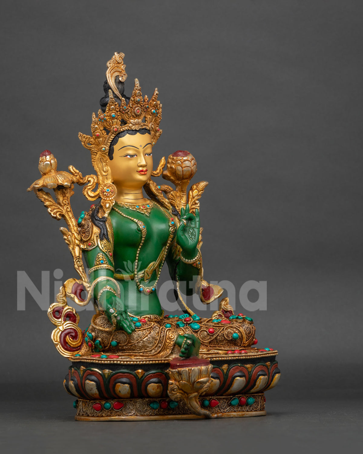 Green Tara statue displaying Varada Mudra and holding an utpala lotus.