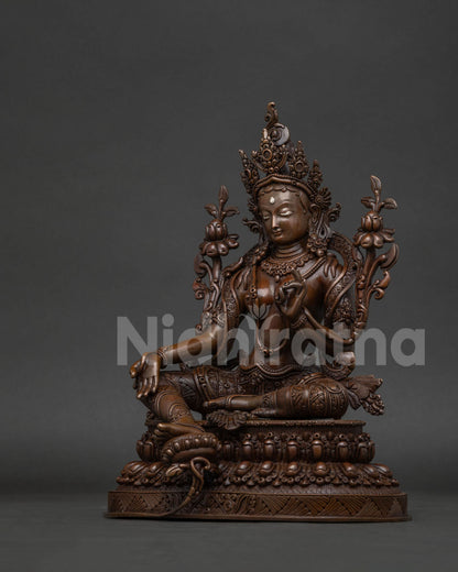 Green Tara statue with five jewel crown and floral patterned robe.