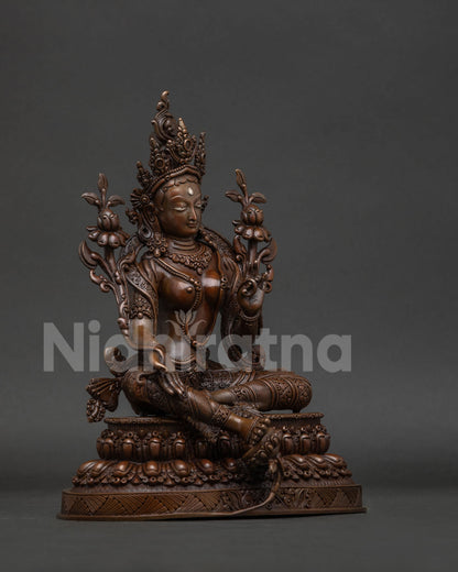 Green Tara statue with varada mudra and blooming utpala lotus.