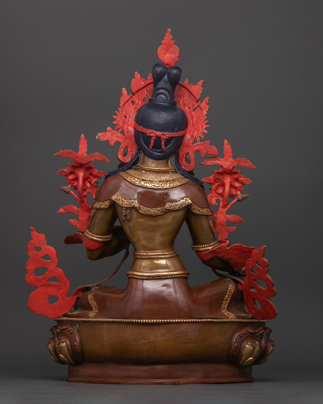 the back side of oxidized copper statue of green tara showing some acrylic painted parts