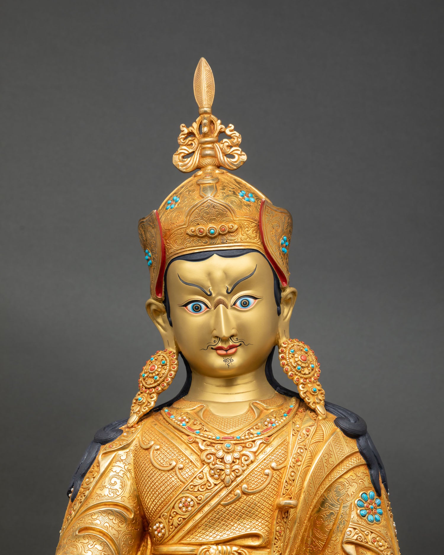 Guru Padmasambhava close up gold painted face semi precious stones Himalayan statue