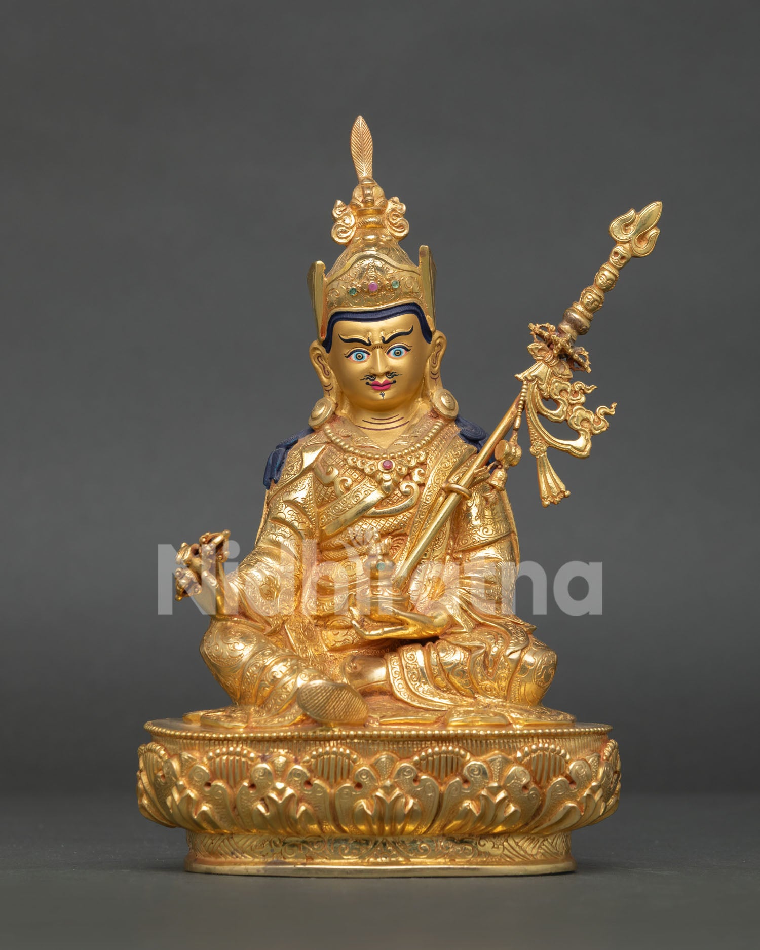 Guru padmasambhava statue holding vajra trident and skull cup with vase in himalayan art.