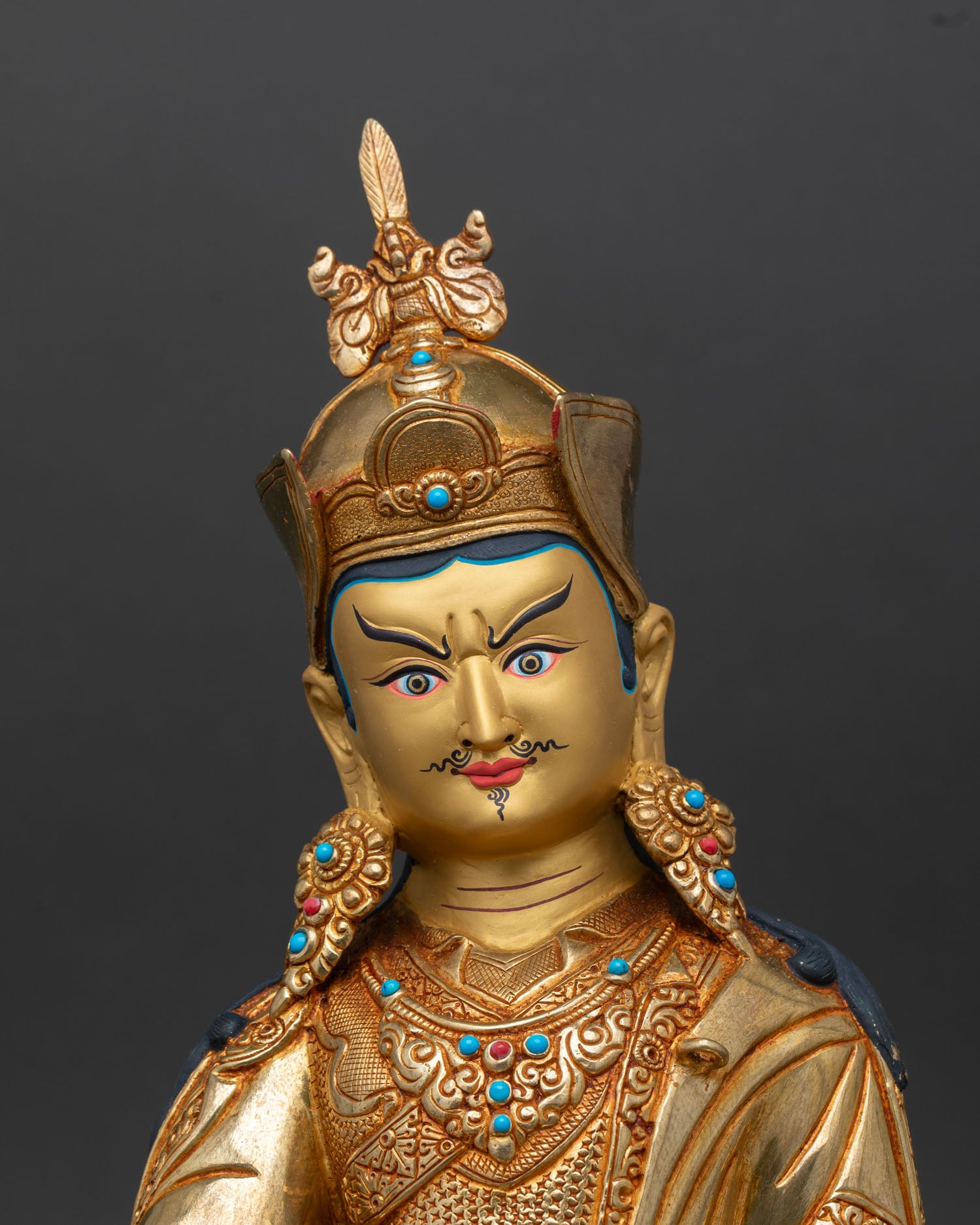 Guru Rinpoche face close up gold painted serene commanding expression detailed Tibetan iconography 