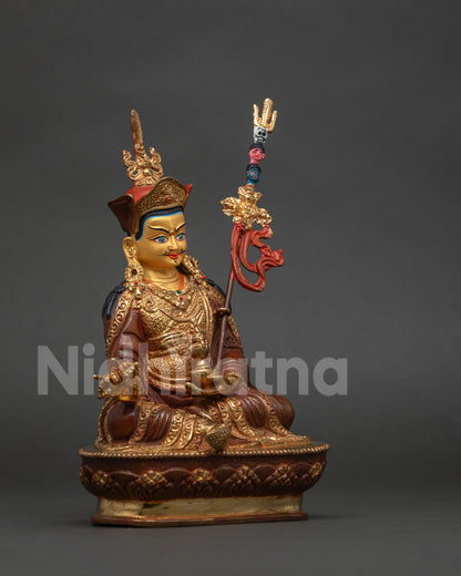 Guru Rinpoche Padmasambhava statue holding vajra and sacred skull cup with khatvanga staff.