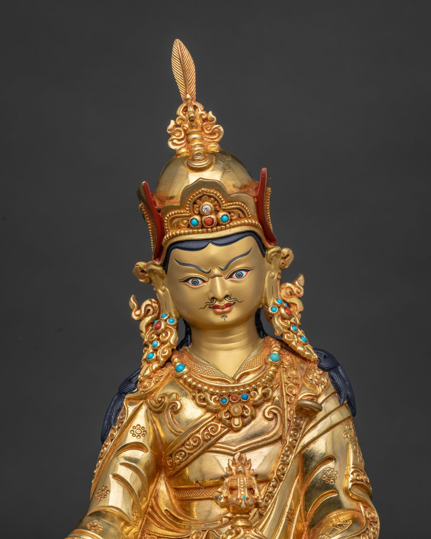 Guru Rinpoche Padmasambhava statue with gold painted face red lotus hat and vajra.