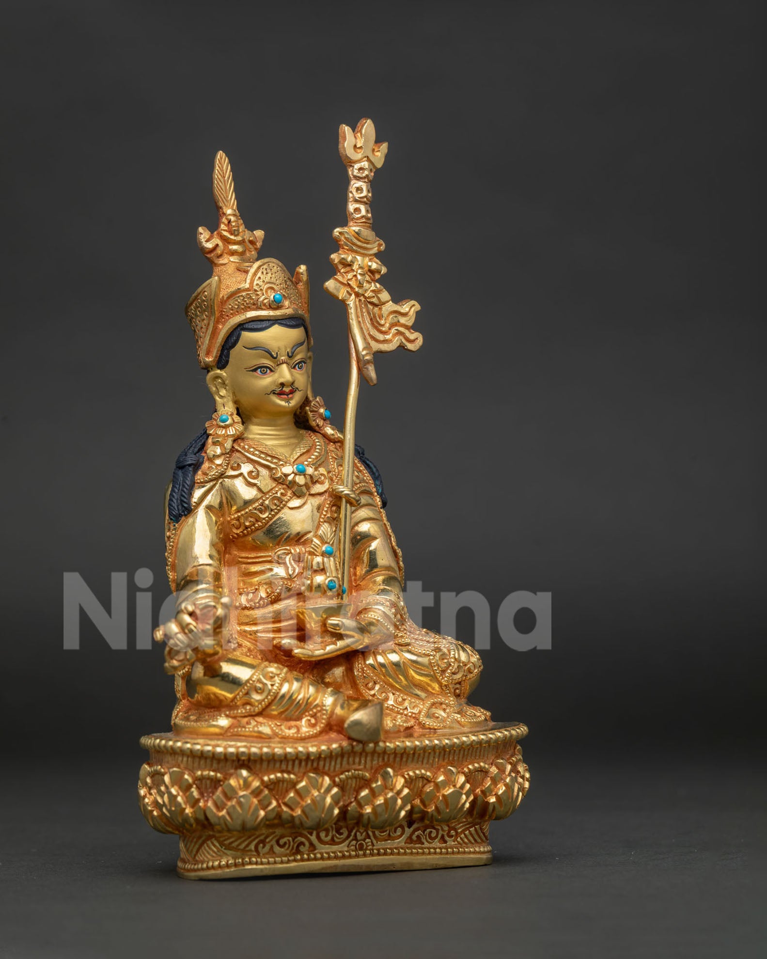 Guru Rinpoche Padmasambhava statue with red lotus hat vajra skull cup and khatvanga staff.