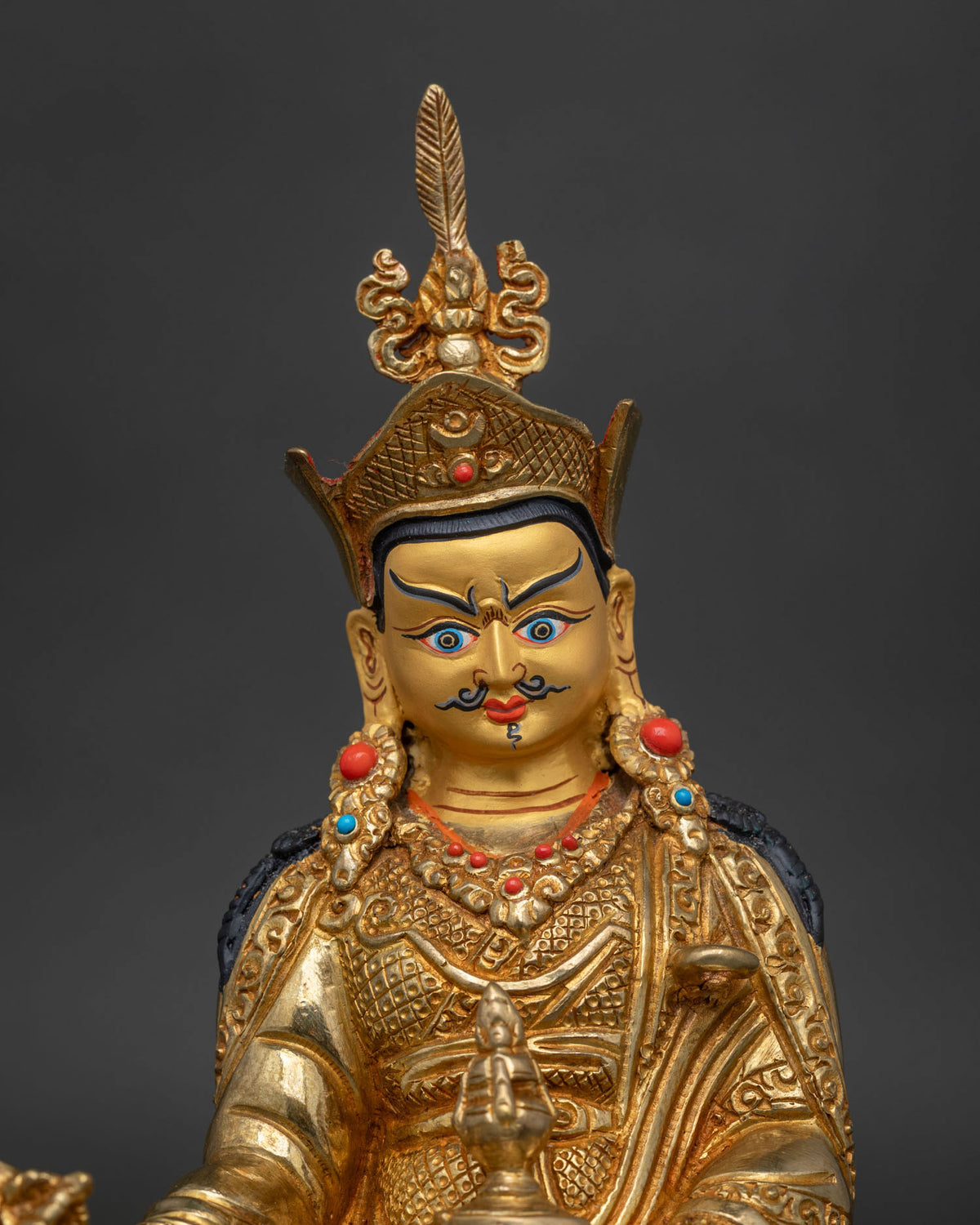Guru rinpoche statue 24k gold face semi precious stones close up.