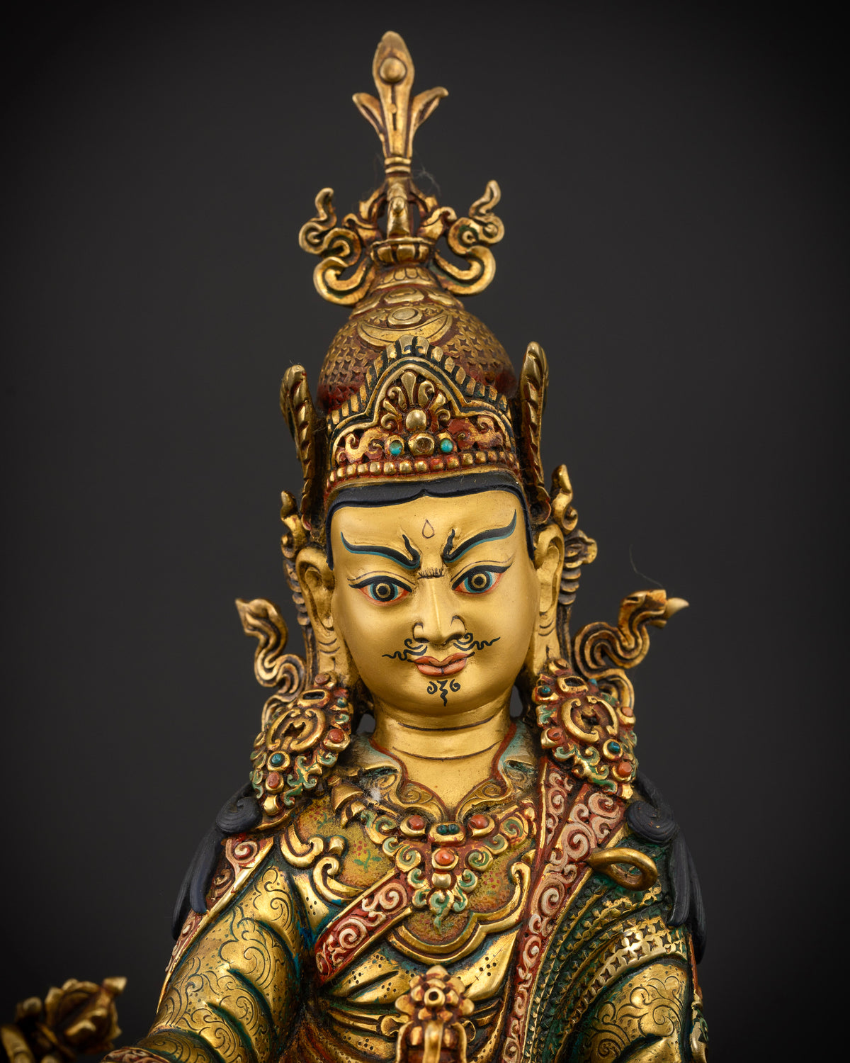 Guru Rinpoche statue featuring a 24K gold painted face ornate crown and semi precious stone details.