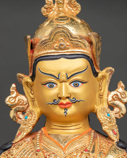 Guru Rinpoche statue close-up featuring a gold-painted face, jeweled lotus hat, and ornate necklace