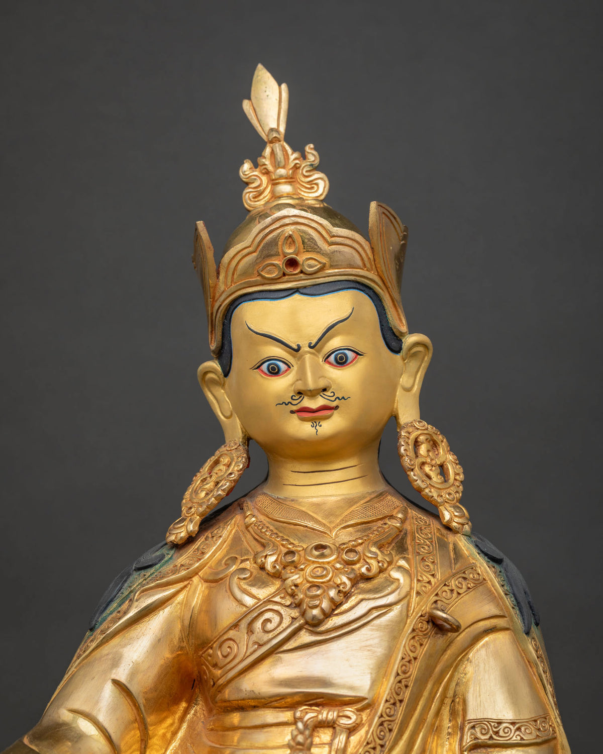 Guru Rinpoche Statue close up gold gilded details and ornaments.