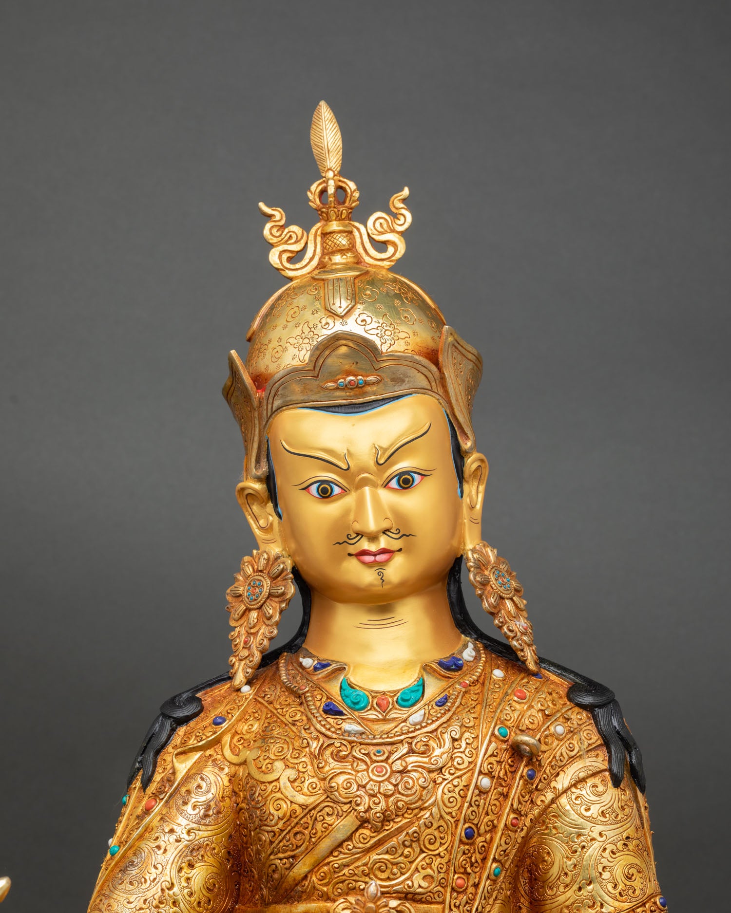 Guru Rinpoche statue close up gold gilded face detail ceremonial robes floral motifs scrolling patterns himalayan art
