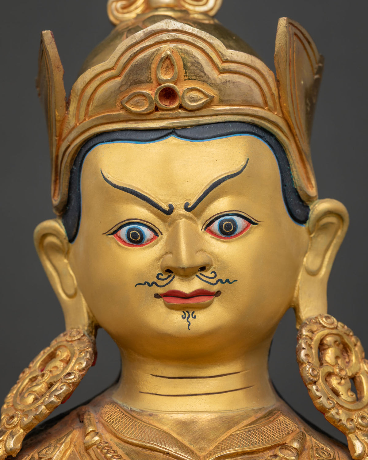 Guru Rinpoche Statue face close up 24k gold painted face and mustache.