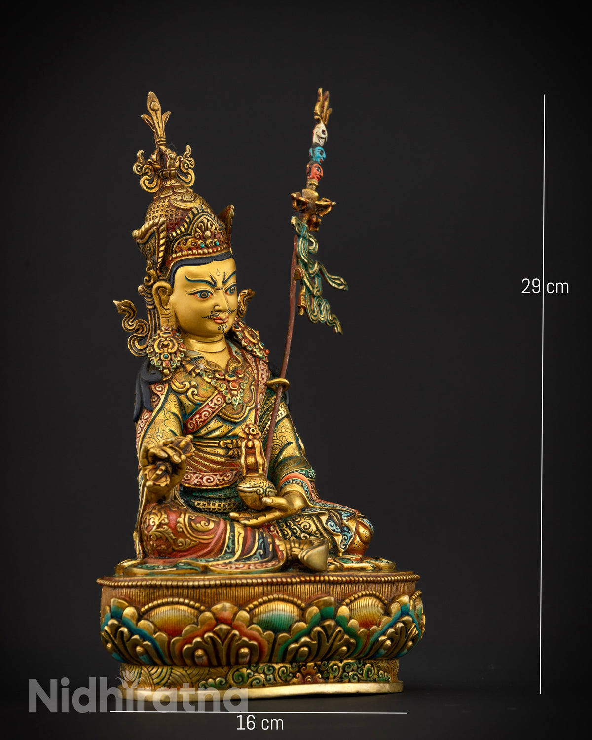Guru Rinpoche statue holding a vajra thunderbolt scepter in his right hand and a skull cup in his left.