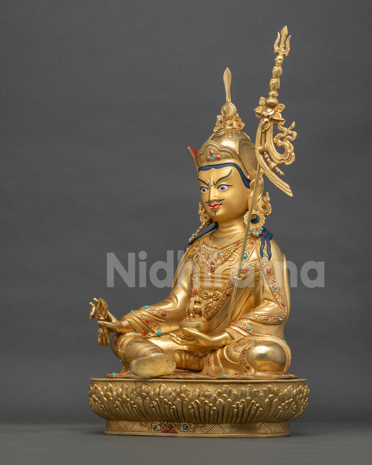 Guru Rinpoche statue left side view, jeweled robes and khatvanga staff, gold fire-gilded copper