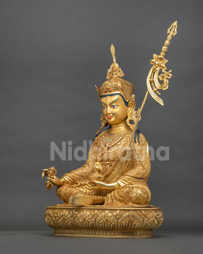 Guru Rinpoche statue left side view, skull cup, khatvanga staff and lotus pedestal, gold fire-gilded