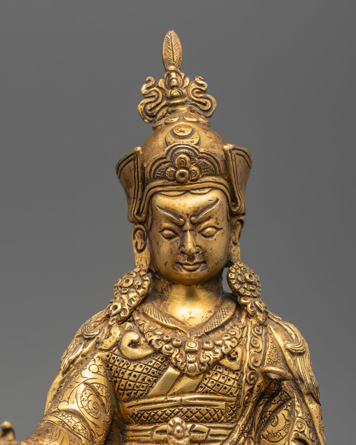 Guru Rinpoche statue seated on hand carved lotus pedestal with khatvanga staff.