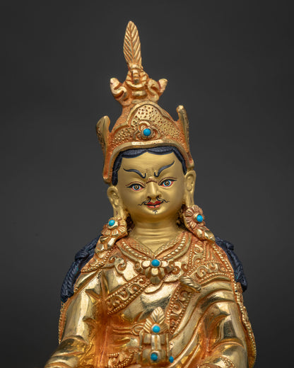 Guru Rinpoche statue showing gold painted face and semi precious stone details.