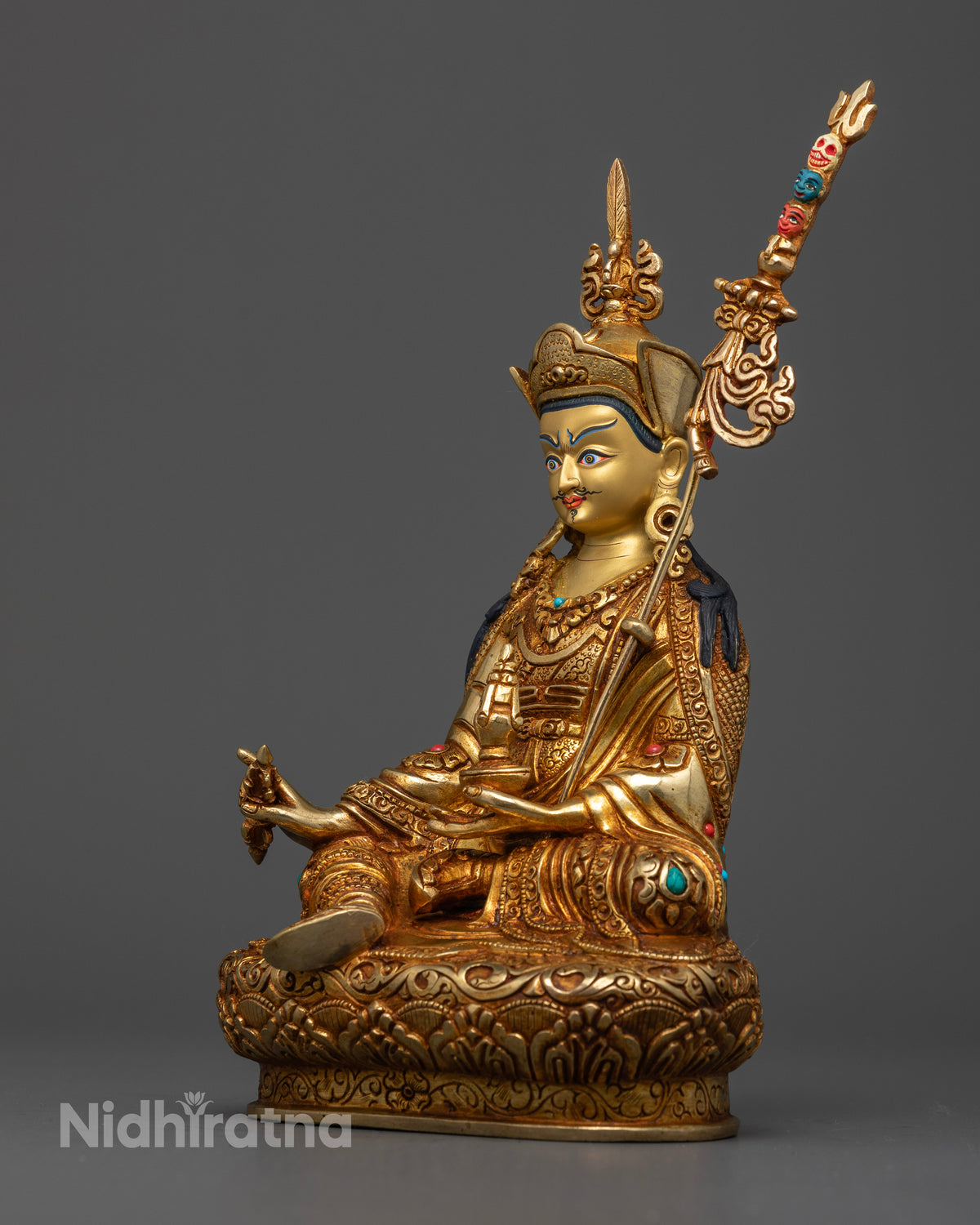 Guru Rinpoche statue holding a vajra and skull cup with a sacred trident
