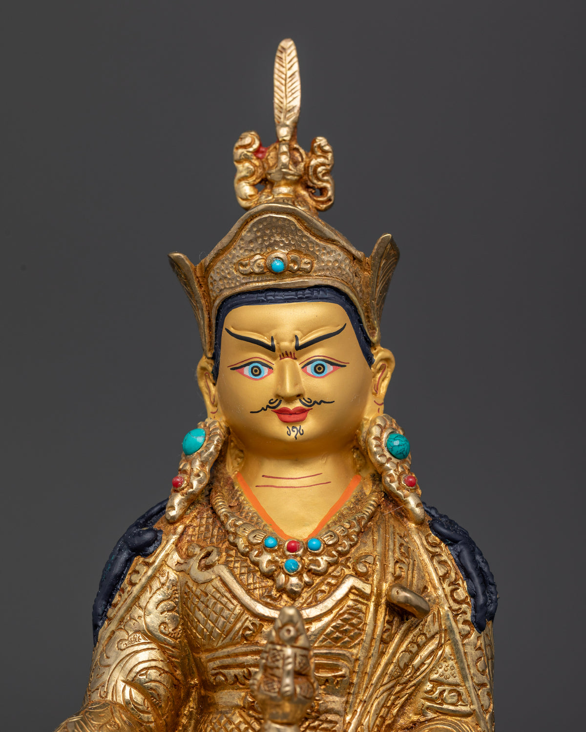 Guru Rinpoche statue wearing lotus hat holding vajra and kapala.