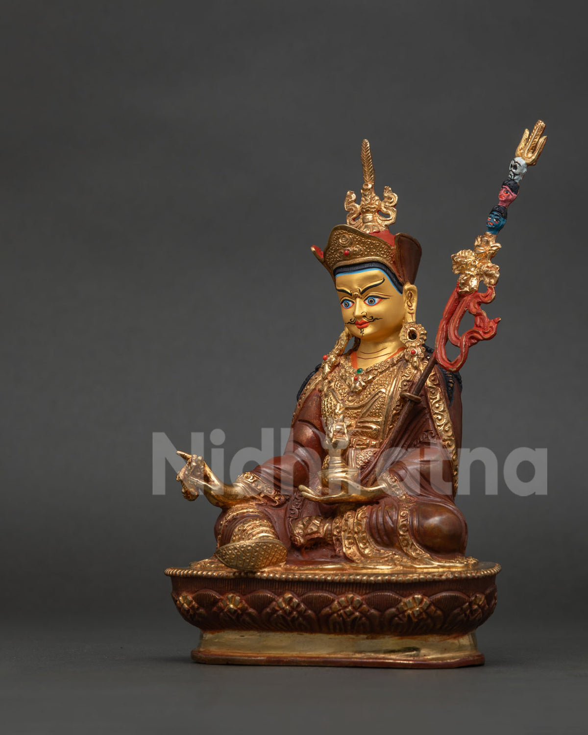 Guru Rinpoche statue with red lotus hat and vulture feather in semi wrathful Vajrayana form.