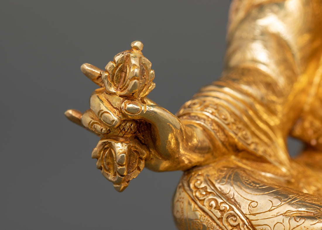 the hand of guru rinpoche statue showing him holding a five pronged bajra