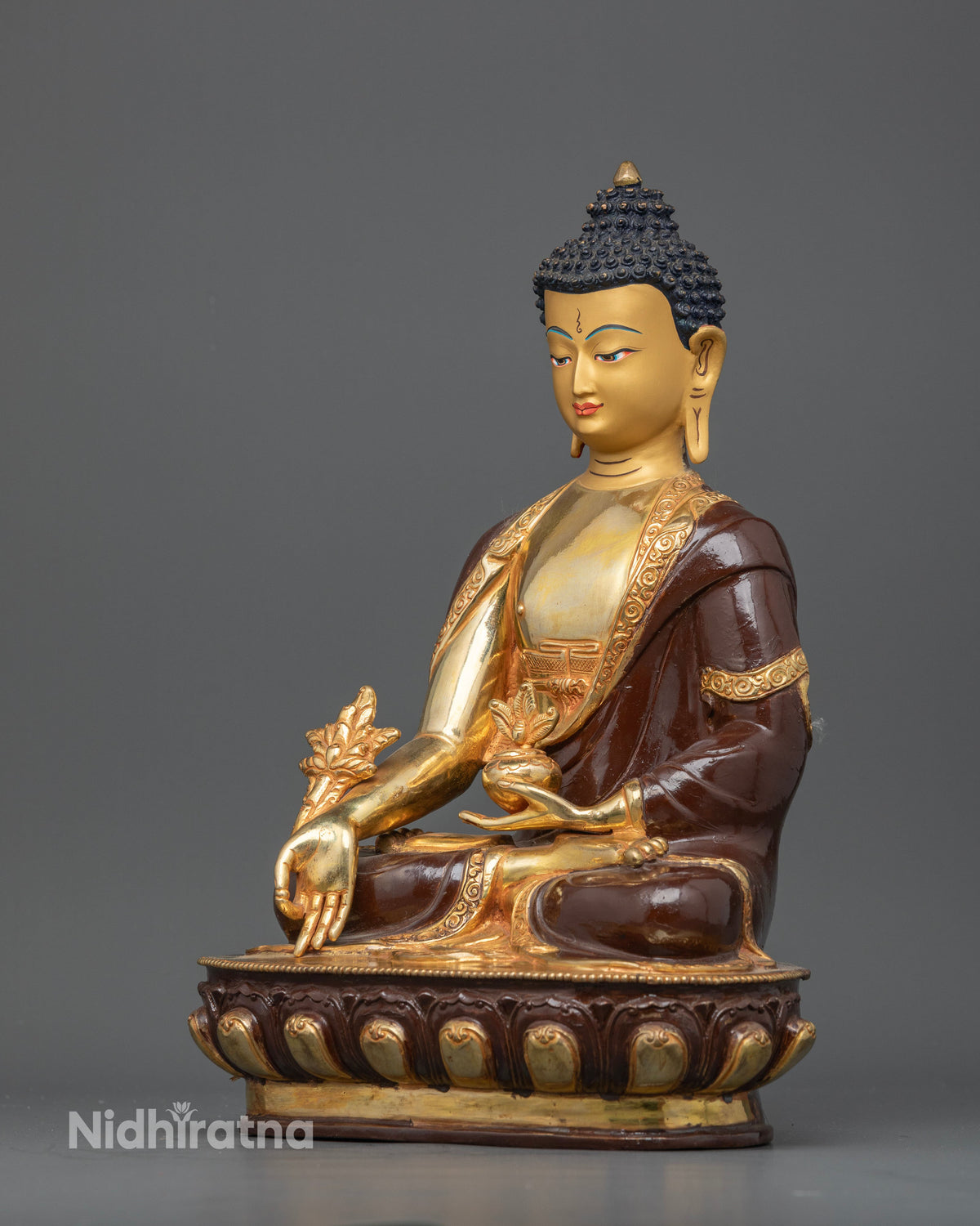 Half oxidized Medicine Buddha statue featuring gold fire gilding and a detailed Buddhist robe.