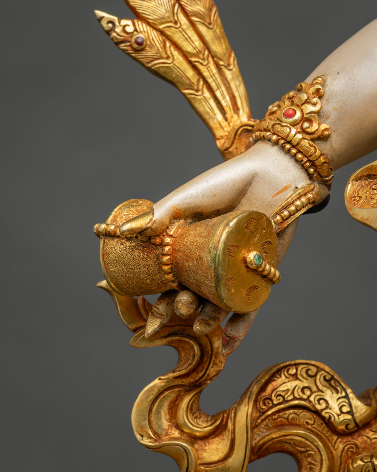 Hand of White Mahakala statue holding a damaru, gilded and set with semi-precious stones
