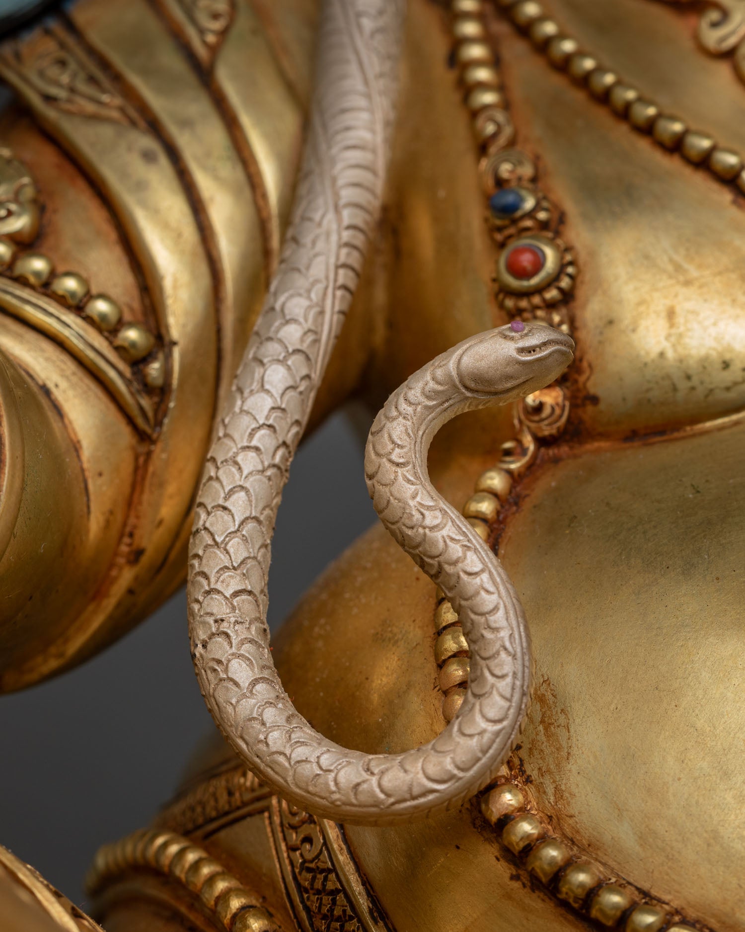 Hand-painted serpent coiling across Dzambhala Statue's shoulder and arm