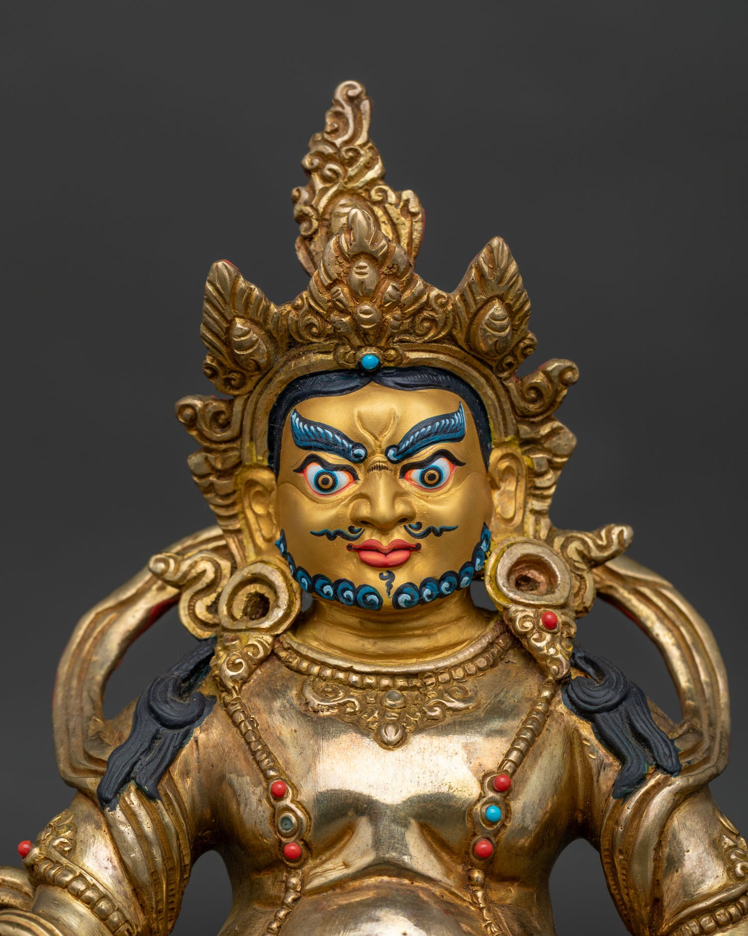 Handcrafted Dzambhala statue showing gold painted face and sacred Buddhist details.