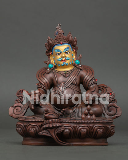 Handcrafted Dzambhala statue with oxidized copper finish and gold painted face.
