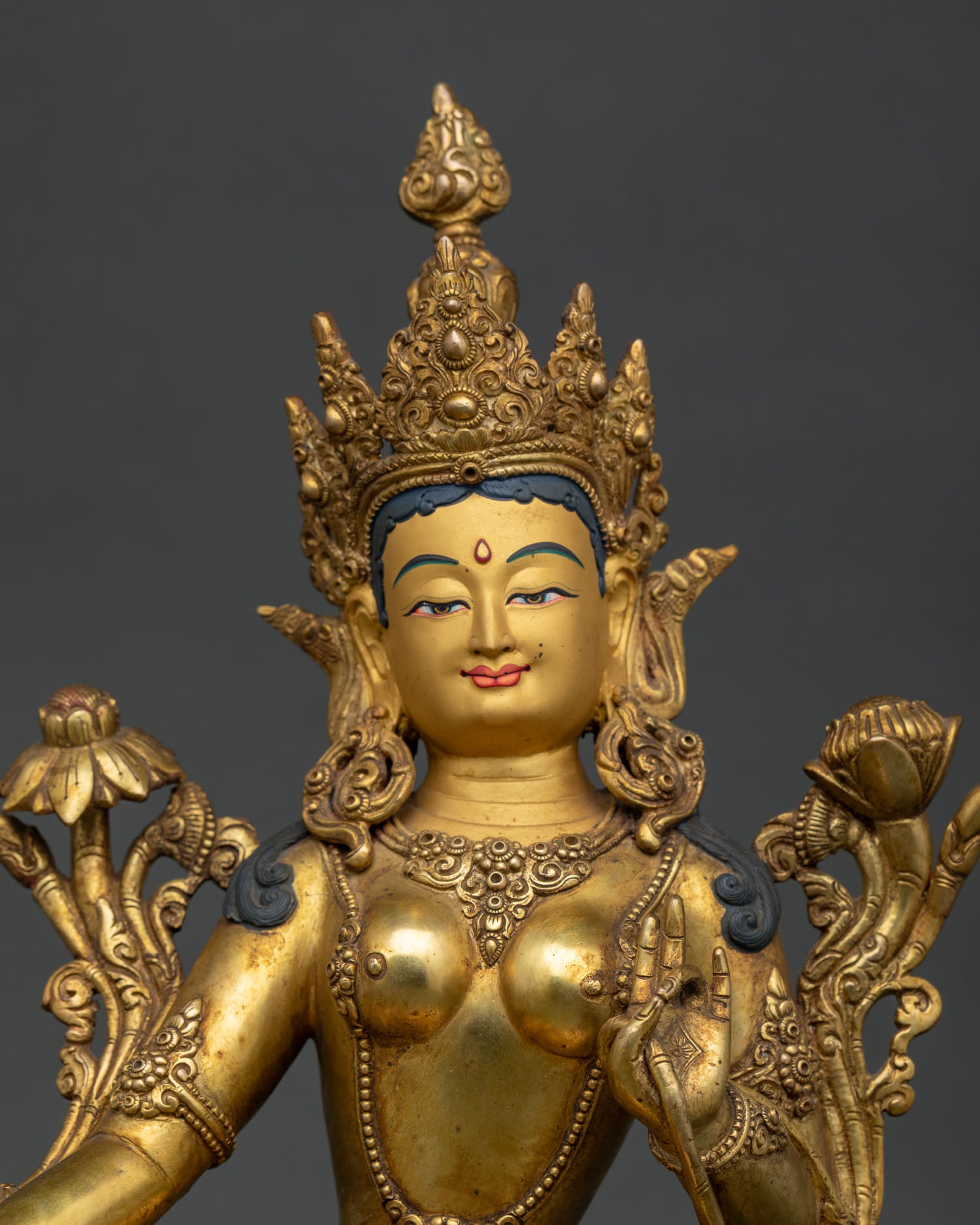 Handcrafted green tara statue with gold painted face and jeweled crown.
