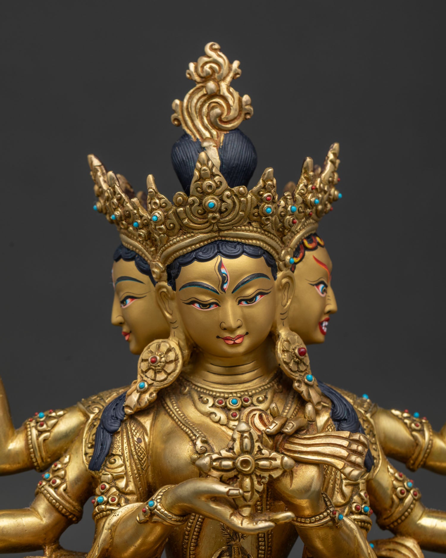 Handcrafted Namgyalma statue close up showing three faced expression gold painted face and semi precious stones.